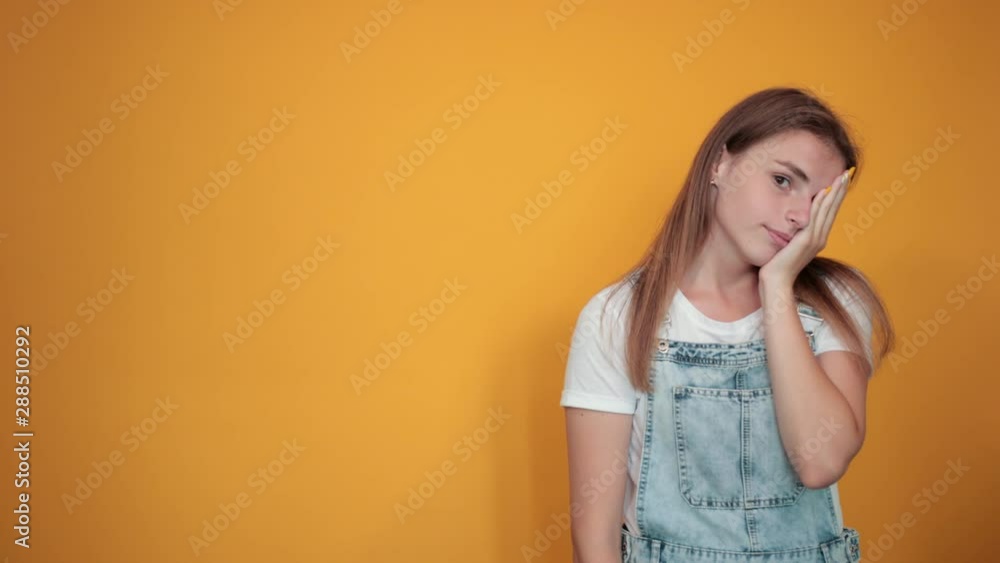 Young woman wearing white t-shirt, over orange background shows emotions Young woman wearing white t-shirt, over orange background shows emotions
