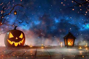 Halloween pumpkins on dark spooky forest with blue fog in background.