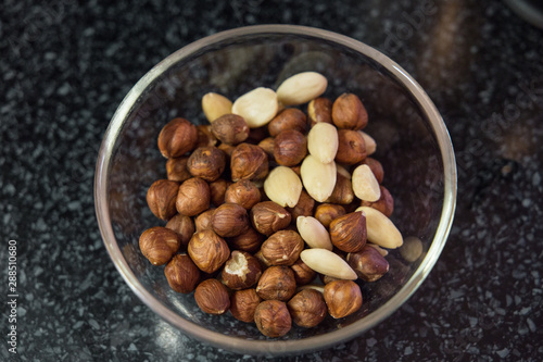 Nuts in transparent glass bowl on the dark table