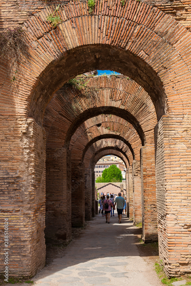 Tourists walking by the archway at Via Nova on the ancient Roman Forum in Rome