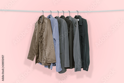 Men s suits and jackets hung on clothes hangers isolated on pink pastel color background  with clipping path.