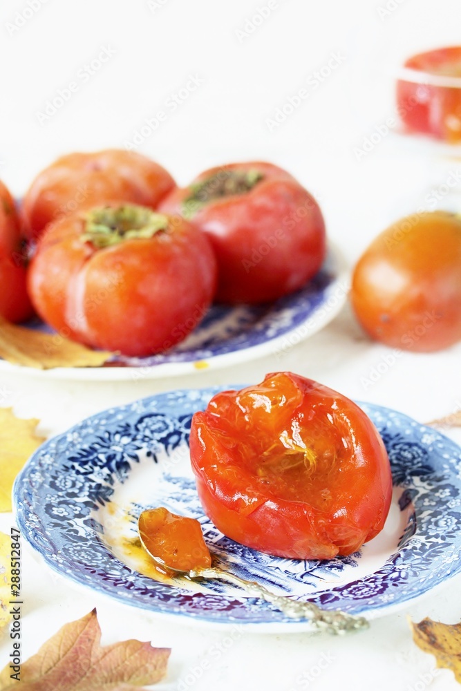 ripe juicy persimmons on a light background. You can eat with spoons like jelly. autumn still life flat. autumn leaves. ripe juicy persimmons on a light background. You can eat with spoons like jelly. autumn still life flat. autumn leaves.