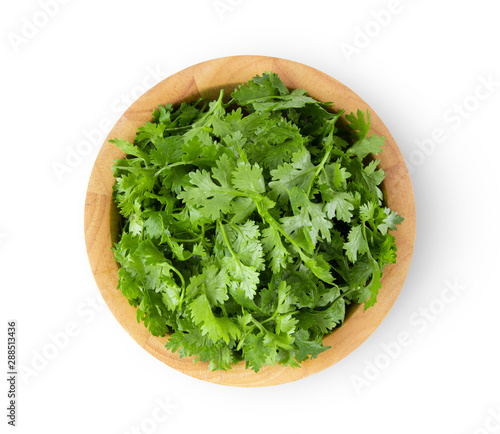 coriander leaf in wood bowl isolated on white background. top view