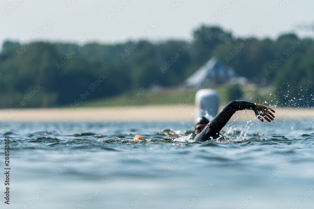 Athletes in wetsuits swimming in a lake