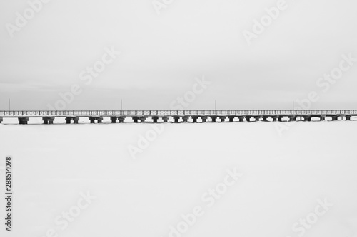 Bridge on the frozen lake. footbridge dividing the horizon. conceptual minimalistic image. black and white background