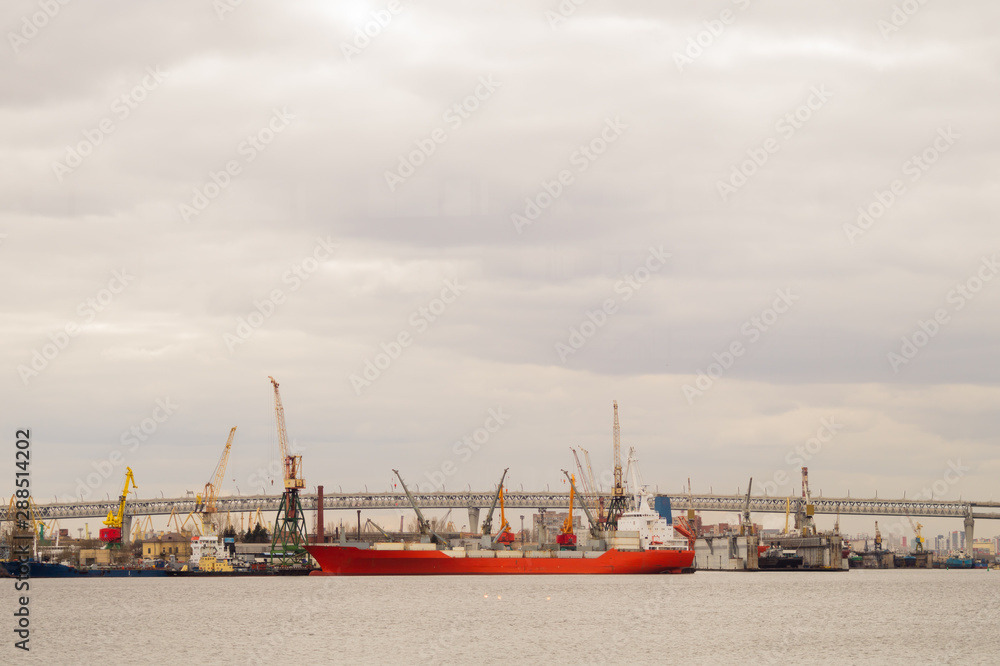 Red cargo ship in the harbor. bridge across the river with industrial works