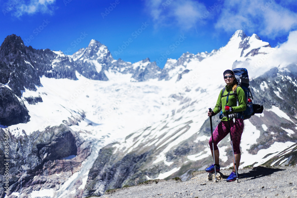 Traveling girl with backpack hiking in the mountains, freedom concept. Hiking people on Asia. Beautiful young woman traveler with a backpack looks at the mountain top before climbing Traveling girl with backpack hiking in the mountains, freedom concept. Hiking people on Asia. Beautiful young woman traveler with a backpack looks at the mountain top before climbing
