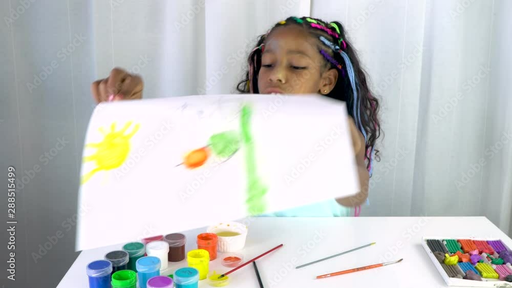 Mixed ethnicity girl with colored braids has finished coloring the image with acrylic paint. Creative activity at home Mixed ethnicity girl with colored braids has finished coloring the image with acrylic paint. Creative activity at home