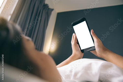 Asian Woman's hands using smartphone with blank screen in bedroom at morning.