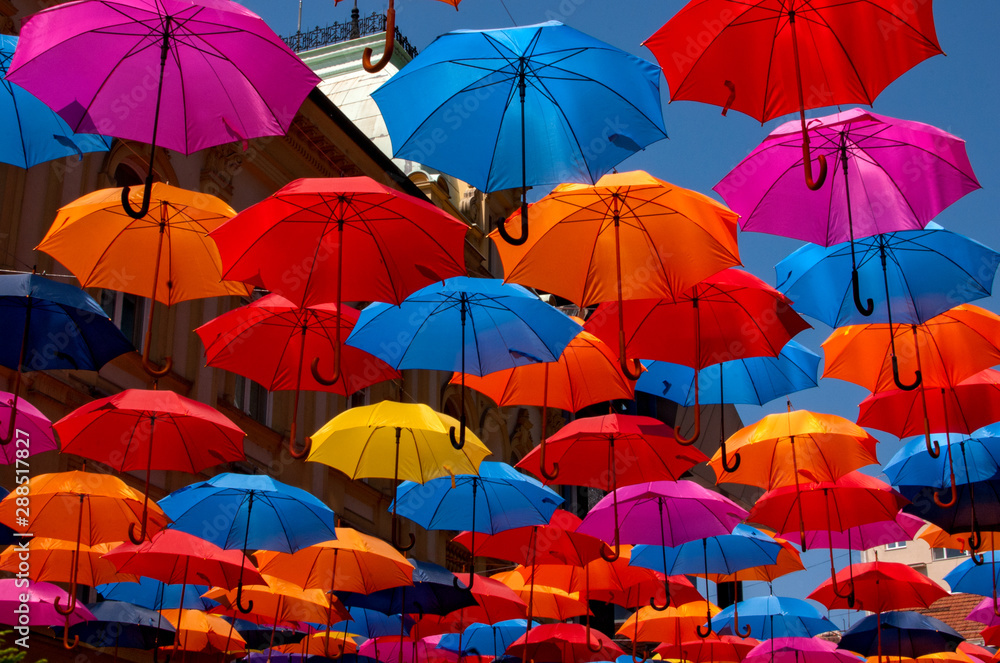 Many colorful umbrellas hanging on the street