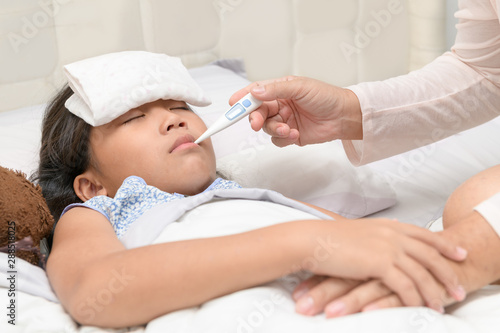 Mother checking temperature of her sick daughter.