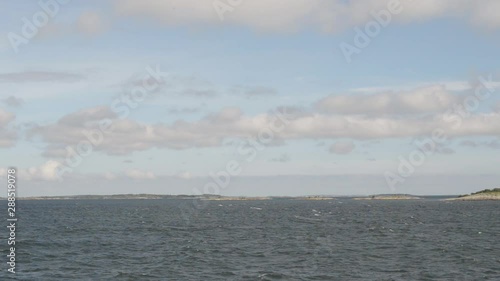 A  view from a ship with small islands going by in the horizon on a sunny day in the arhipelago of Turku. photo
