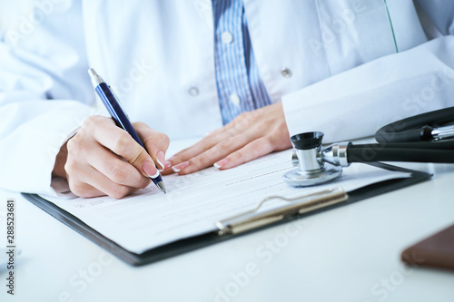 Female medicine doctor hand holding silver pen writing something on clipboard closeup.. Ward round, patient visit check, medical calculation and statistics concept.