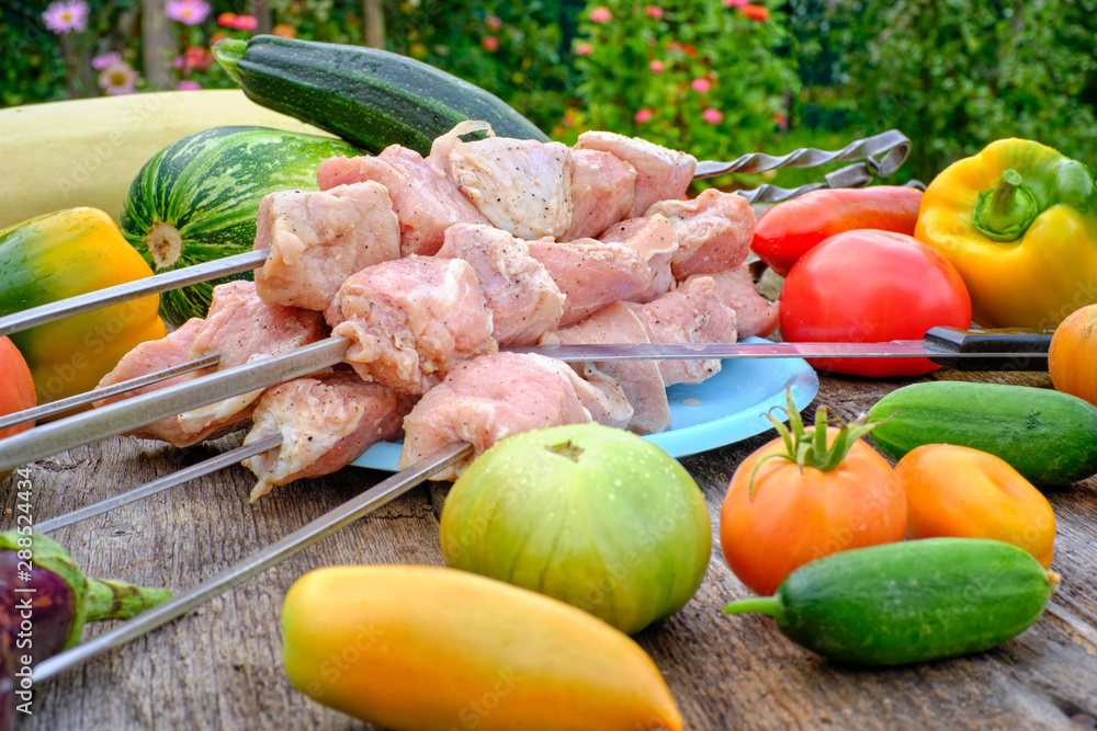 Raw meat for barbecue, lying on an old wooden table in the various derevenskih seasonal vegetables Raw meat for barbecue, lying on an old wooden table in the various derevenskih seasonal vegetables