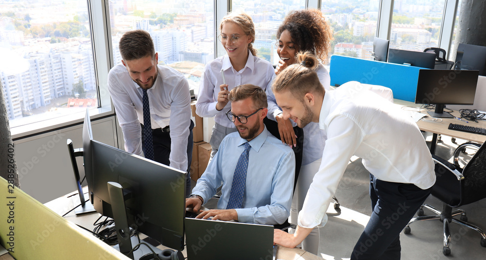 Group of young modern people in formalwear using modern technologies while working in the creative office Group of young modern people in formalwear using modern technologies while working in the creative office