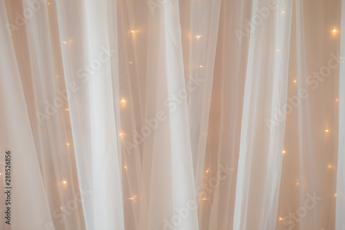 Transparent tulle with lights at the wedding ceremony, a place for photographing the groom, bride or guests