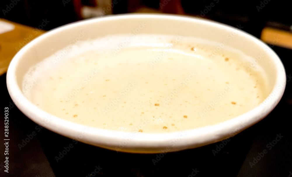 Top view close-up of a paper cup of coffee with milk and foam on a dark background of cafe interior Top view close-up of a paper cup of coffee with milk and foam on a dark background of cafe interior