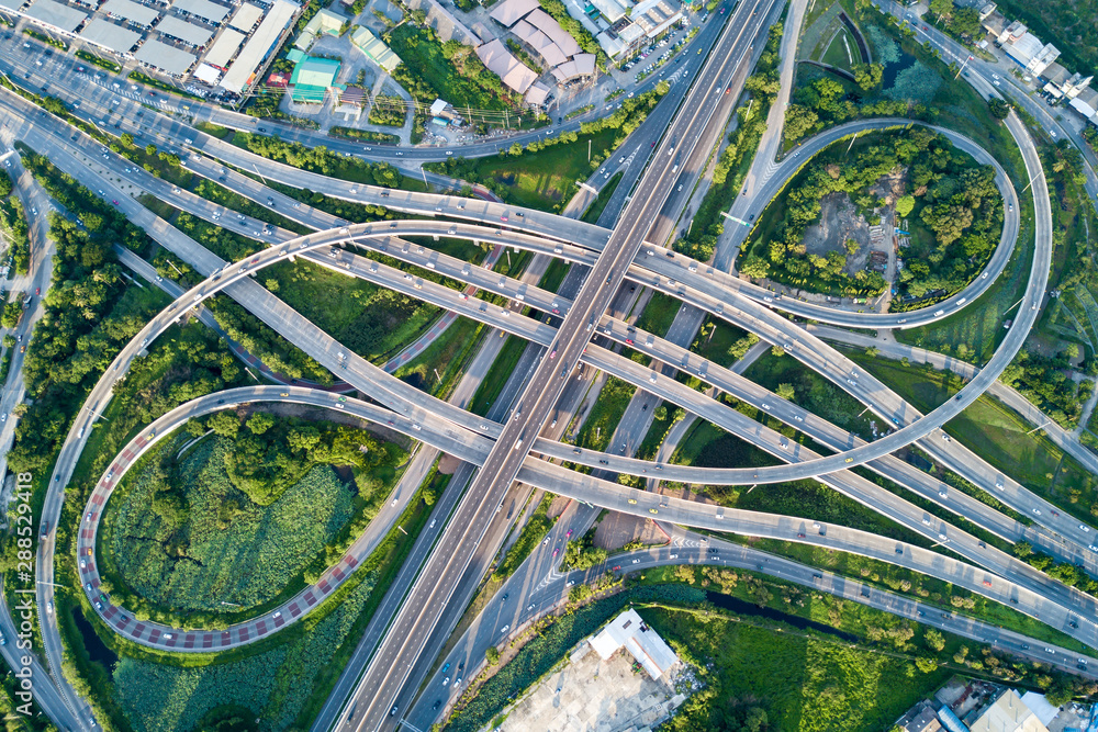 Aerial view of road interchange or highway intersection with busy urban traffic speeding on the road. Junction network of transportation taken by drone. - obrazy, fototapety, plakaty 