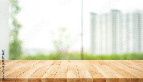 Real wood table top texture on blur leaf tree garden and wall building from city,park