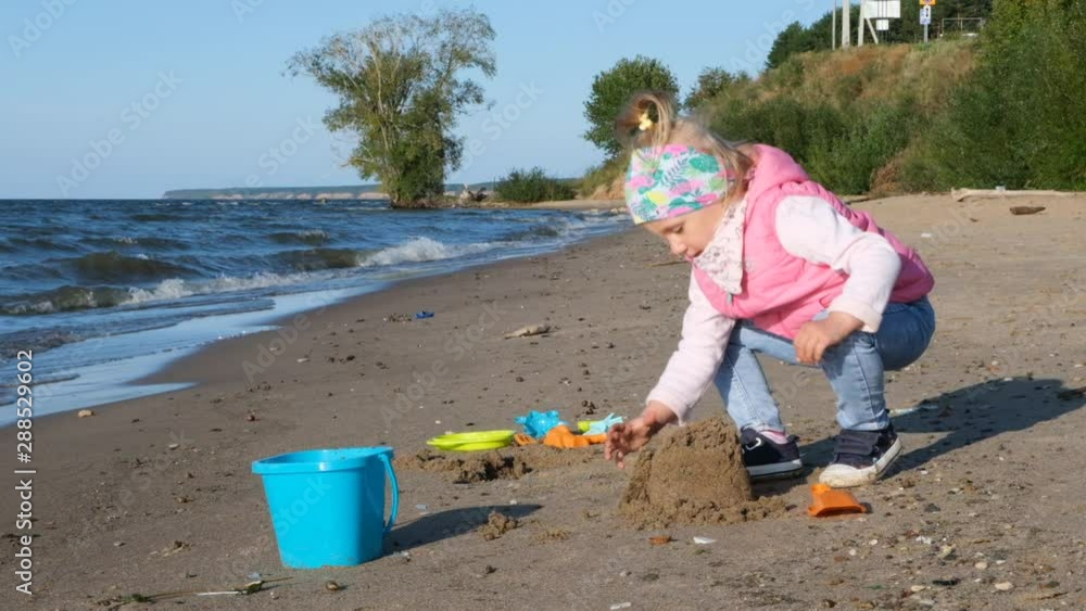 Cute little girl playing along sandy beach in slow motion. Little girl walking along beach. Little girl slowly walking alone at seashore. Child going for a walk on sea waves on beach Cute little girl playing along sandy beach in slow motion. Little girl walking along beach. Little girl slowly walking alone at seashore. Child going for a walk on sea waves on beach