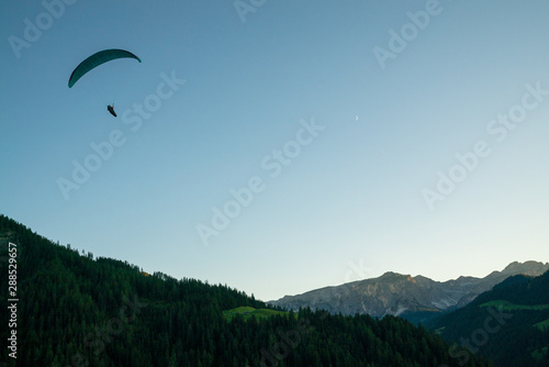 silhouette of paraglider in Dolomite mountain landscape in evening light