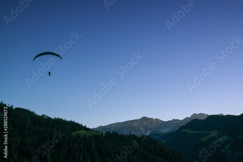 silhouette of paraglider in Dolomite mountain landscape at sunset