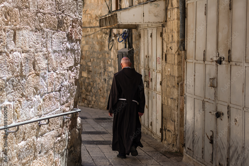 Catholic priest walking on the old narrow street in the Old city of Jerusalem Catholic priest walking on the old narrow street in the Old city of Jerusalem