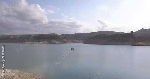 Drone flying over calm water surrounded by nature