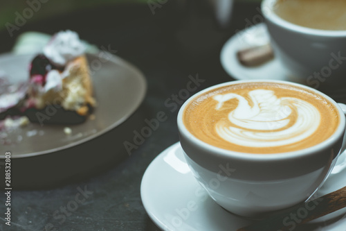 hot art latte heart and blueberry cheesecake on table.