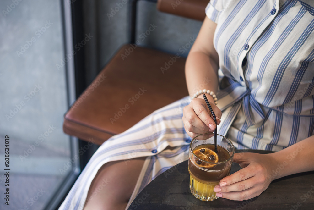 Obraz premium Woman holding a cold summer cocktail with coffee beans
