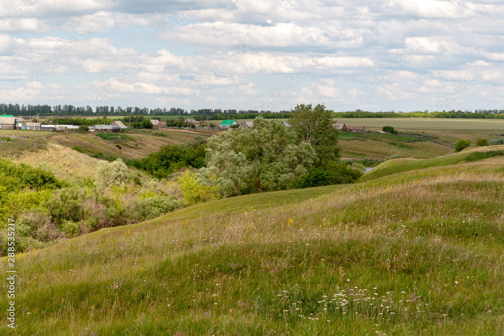 Rugged terrain. Rural landscape with ravines, fields and village in summer noon. Rugged terrain. Rural landscape with ravines, fields and village in summer noon.