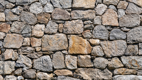 Muro de contenci  n de piedras grandes planas  con diferentes colores y tama  os