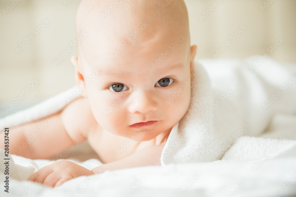 Happy baby with a towel after the shower in bed at home Happy baby with a towel after the shower in bed at home