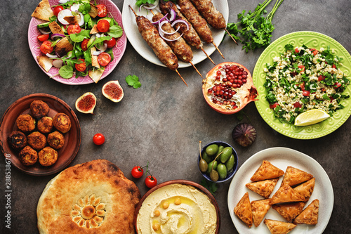 Assorted variety of Arabic and Middle Eastern food on a dark rustic background. Hummus,tabbouleh salad, salad Fattoush,pita,meat kebab,falafel,baklava. Set of Arabian dishes.Top view.