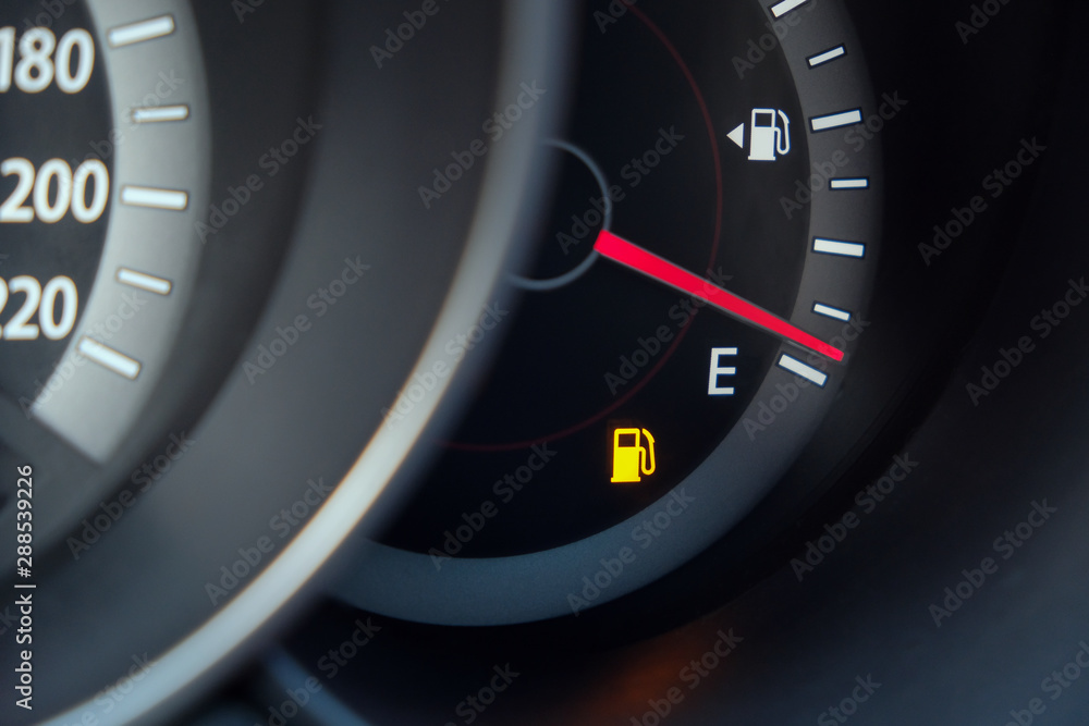 Naklejka premium Fuel gauge with warning indicating low fuel tank