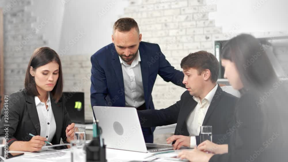 Stylish business people wearing suit talking with male teamleader having team meeting at office Stylish business people wearing suit talking with male teamleader having team meeting at office