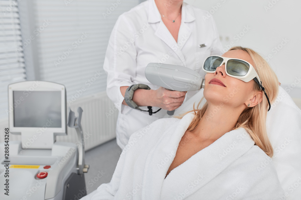 Naklejka premium female client wearing glasses and white bathrobe resting in beauty clinic. close up photo
