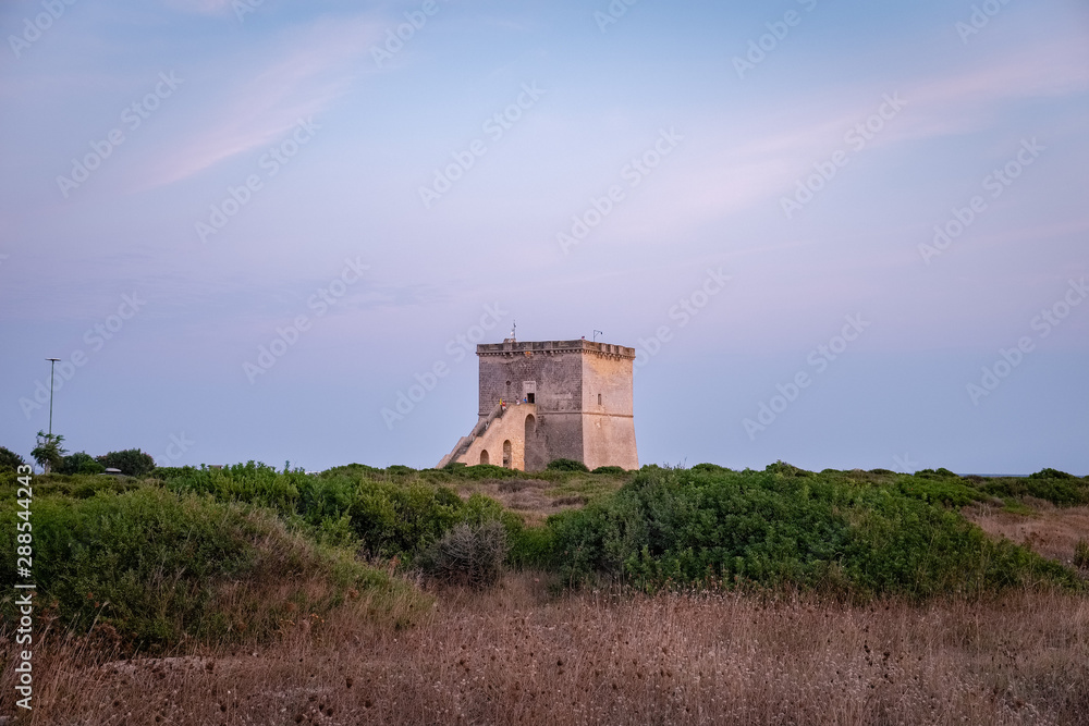View of the ancient defensive coastal tower Torre Lapillo at the sunset. Puglia, Italy View of the ancient defensive coastal tower Torre Lapillo at the sunset. Puglia, Italy
