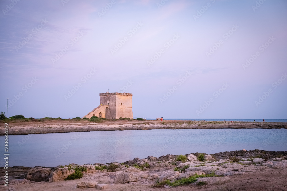 View of the ancient defensive coastal tower Torre Lapillo at the sunset. Puglia, Italy View of the ancient defensive coastal tower Torre Lapillo at the sunset. Puglia, Italy