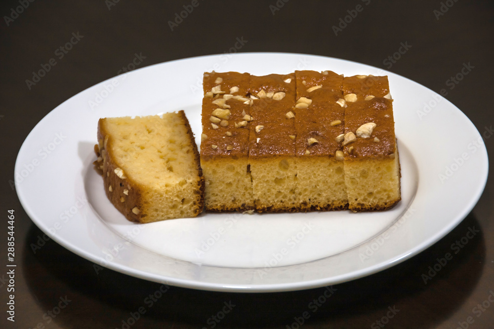 A cut cake with cashew on a white plate