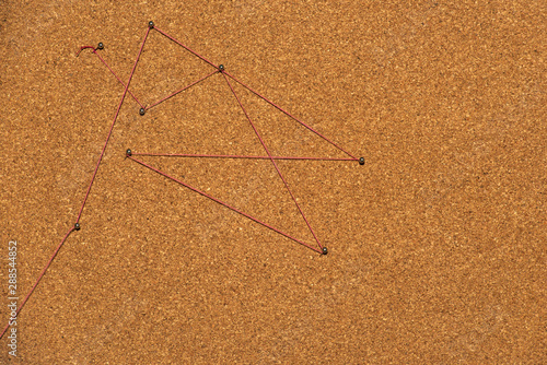 Red thread connects pins on cork board