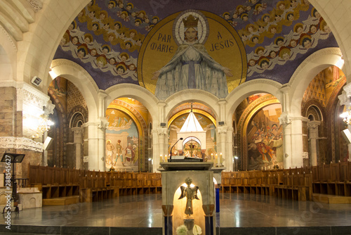 Lourdes, France, 24 June 2019: Interior of the Rosary Basilica, mosaic with the inscription "through Mary to Jesus"