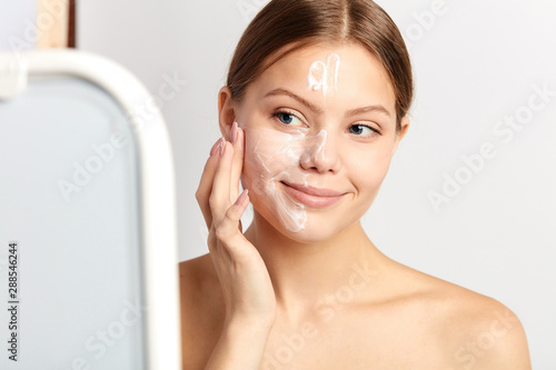 good looking nacked girl taking care of her unhealthy skin, improving her face. close up portrait, isolated white background photo