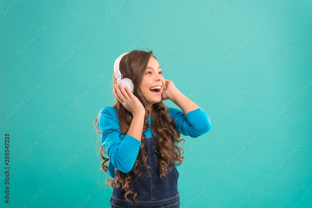 Music sounds better with my headphones. Little girl wearing headphones on blue background. Cute child listening to music in ear stereo headphones. Adorable small kid wearing modern headphones Music sounds better with my headphones. Little girl wearing headphones on blue background. Cute child listening to music in ear stereo headphones. Adorable small kid wearing modern headphones