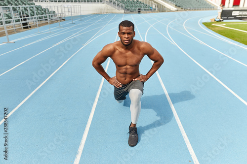 Handsome strong sportsman doing lunges, dressed in sportswear, outdoors, full length photo. hobby, interest