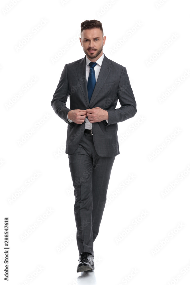 confident young businessman walking and buttoning his suit confident young businessman walking and buttoning his suit