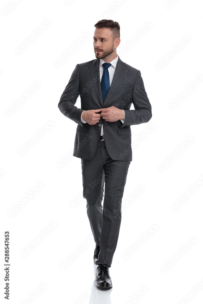 successful young man bussoning his suit and loks to side successful young man bussoning his suit and loks to side