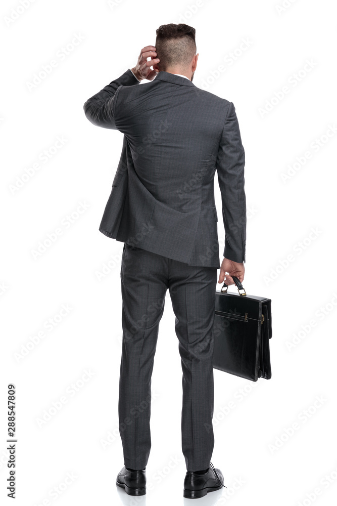back view of a confused businessman scratching his head back view of a confused businessman scratching his head