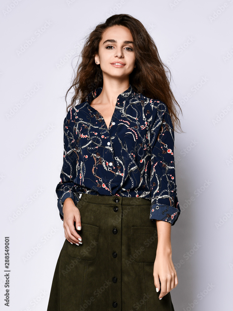 cheerful young woman posing in solitude, in a dark blue silk blouse with floral patterns, a dark short skirt with buttons cheerful young woman posing in solitude, in a dark blue silk blouse with floral patterns, a dark short skirt with buttons
