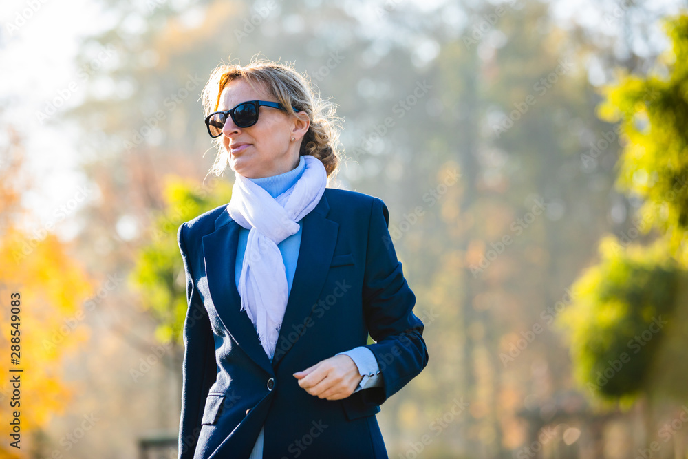 Middle-aged woman walking in city park Middle-aged woman walking in city park